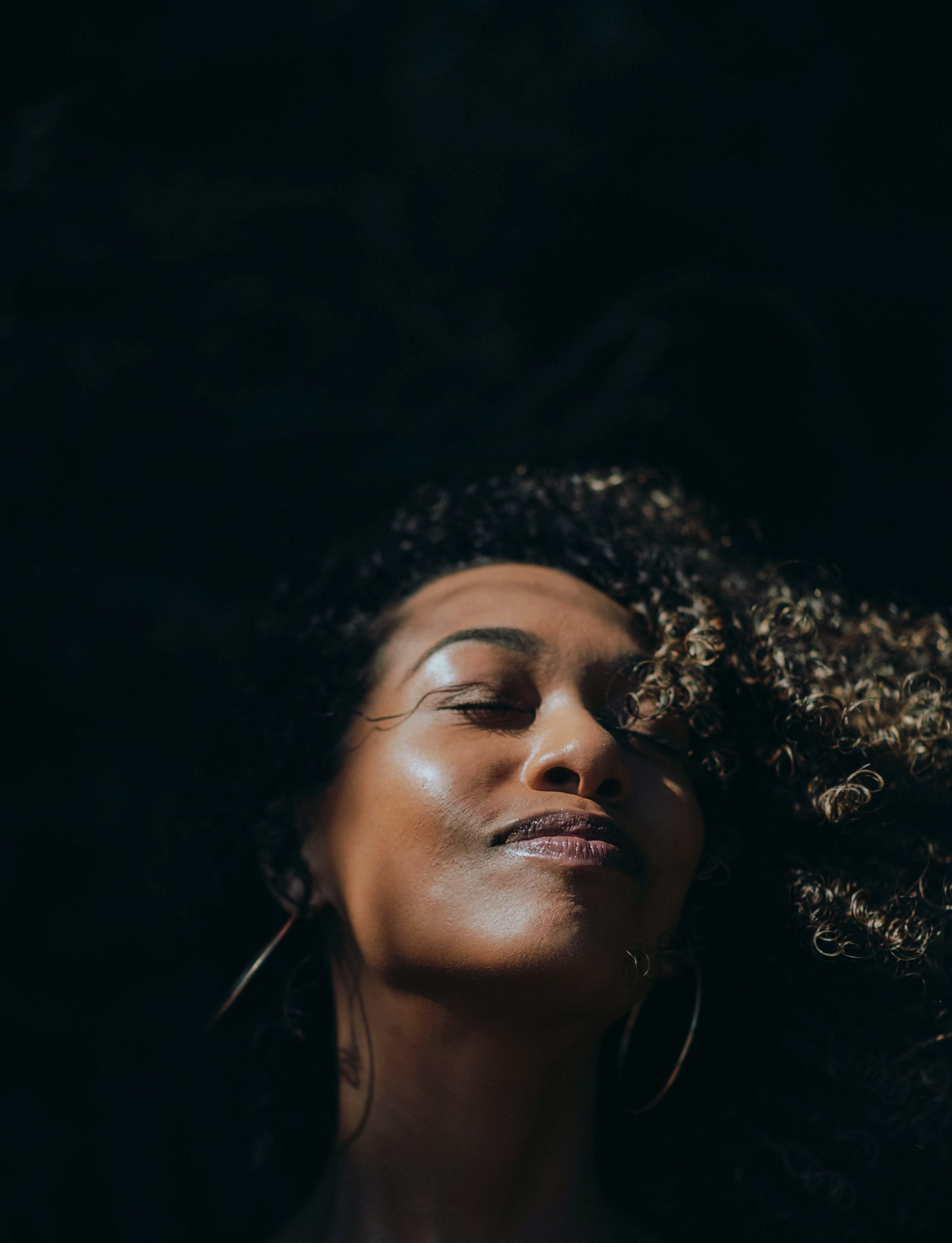Image of a Black woman smiling with her eyes closed. This image illustrates the peace that you can get from trauma symptoms after working with a trauma therapist in Pikesville, MD. Christina uses many tools during trauma therapy in Pikesville, MD.| 21117