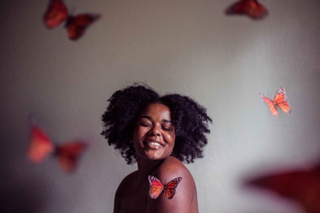 A strong black woman is surrounded by butterflies representing the freedom that can be found through Trauma Therapy in Baltimore, MD. 