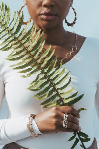 Image of a Black woman holding a plant while wearing with clothing. This image represents an example of a mind-body practice that may be incorporated into EMDR therapy. | 21204 | 21286 | 21044