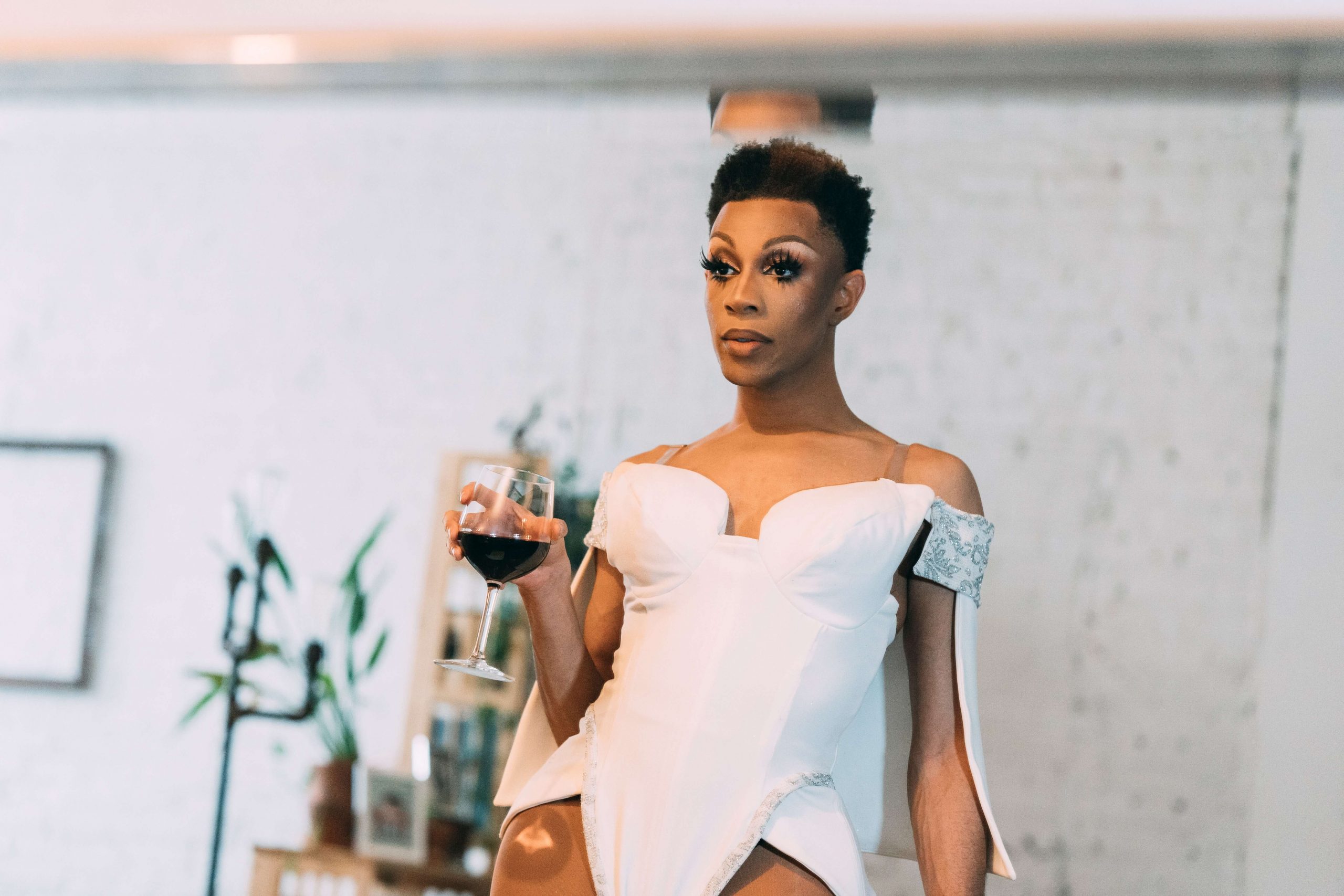 A black trans individual leans against a counter with a glass of wine representing the black LGBTQ community and their increased need for EMDR Therapy in Baltimore, MD to address trauma.