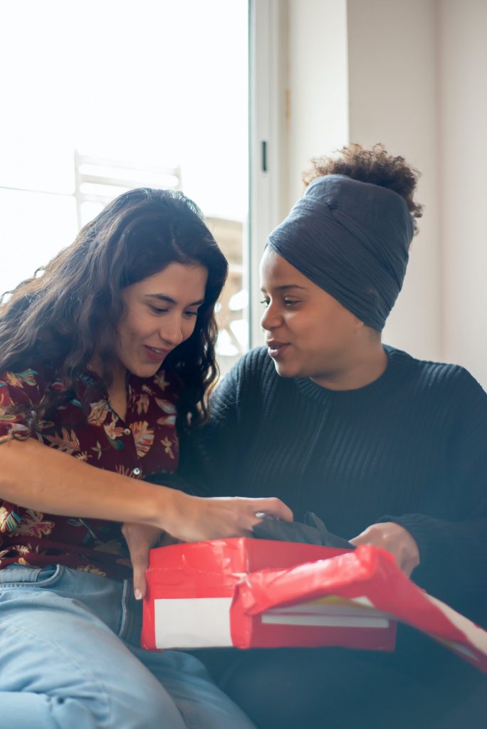 A lesbian couple open gifts during the holiday season. You too can find peace from the holiday stress with the help of an LGBTQ Therapist in Baltimore, MD. 